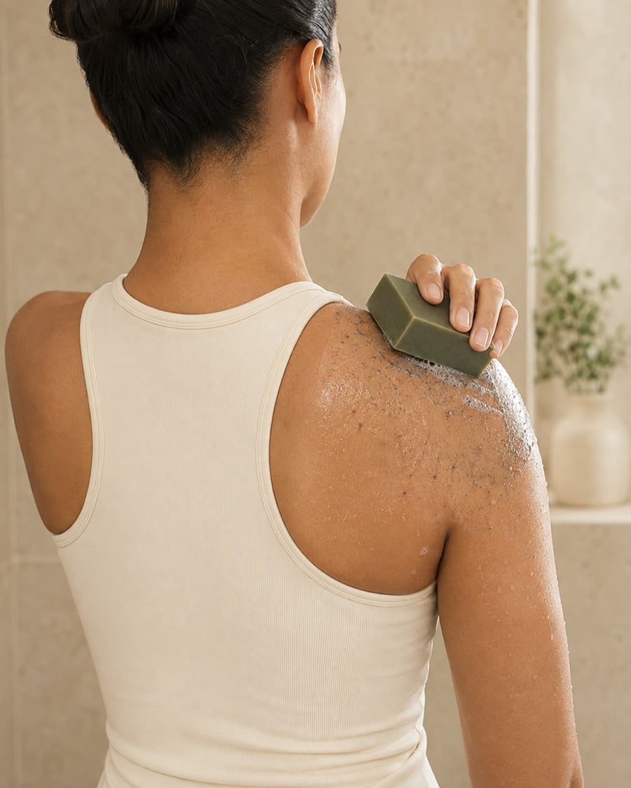 A person washing their shoulder and upper back with the Bamboo Mud bar