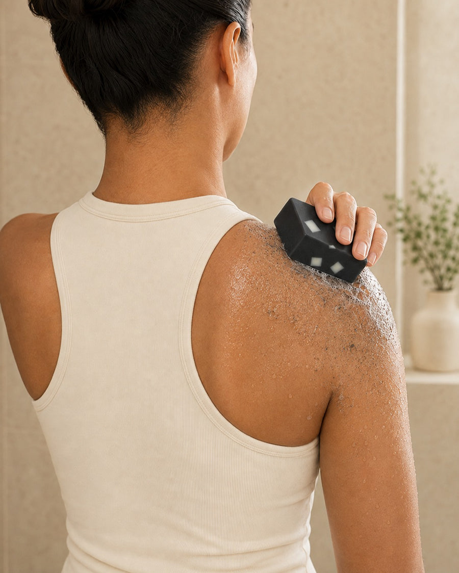 A person washing their shoulder and upper back with the Charcoal Aloe bar